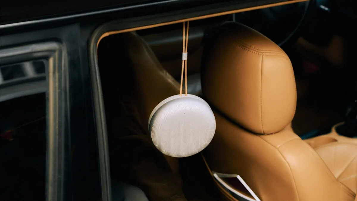 Bang & Olufsen Beosound A1 hanging by its strap inside a car