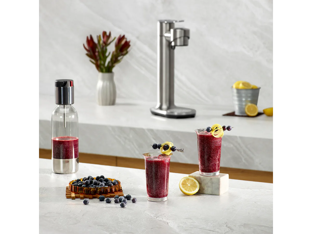 Breville InFizz Fusion with juice, fruit, and drinks on a kitchen counter
