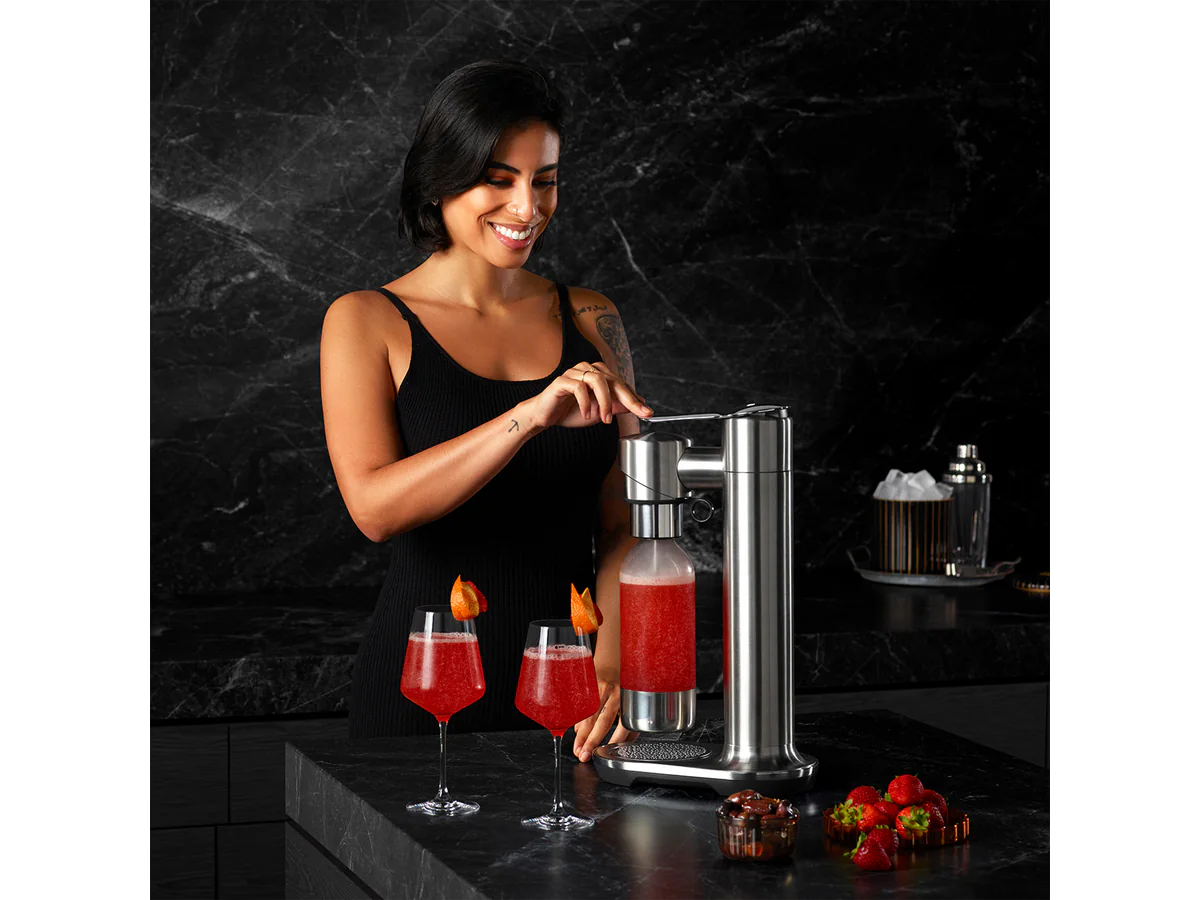 Person using the Breville InFizz Fusion to carbonate a red drink