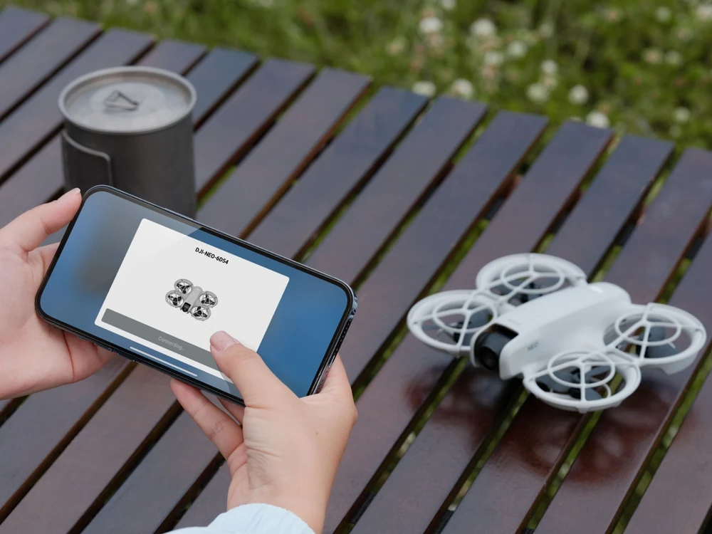DJI Neo beside a phone showing control options