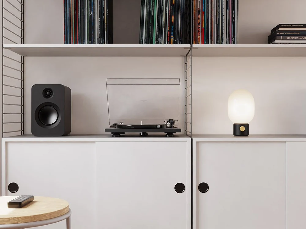 Black Kanto REN speakers on a media cabinet with turntable and records