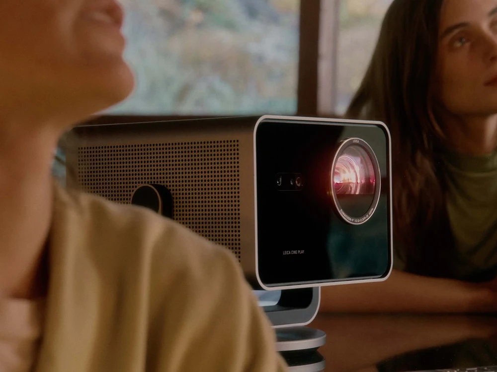Leica Cine Play 1 projector in a living room with people watching a projected image