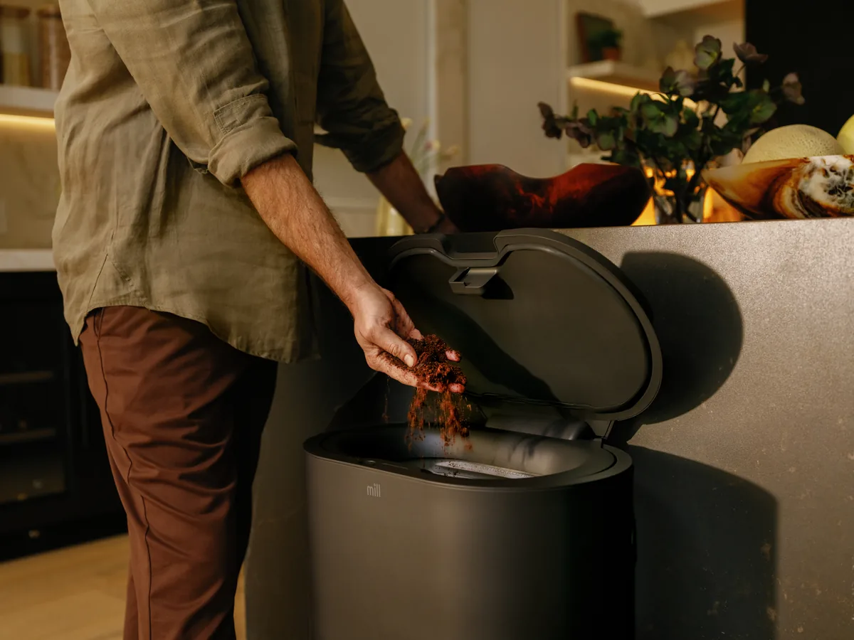 Person adding food scraps into the Mill Food Recycler