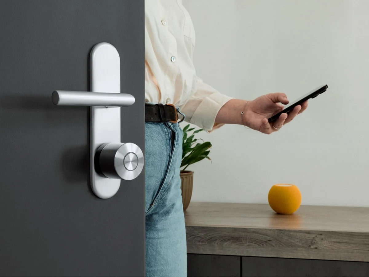 Person using a phone near a door with Nuki Smart Lock Ultra installed