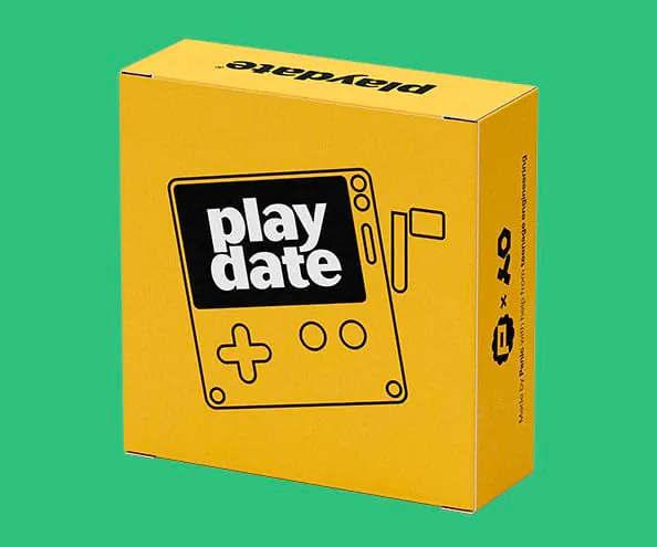 Playdate handheld retail box on green background