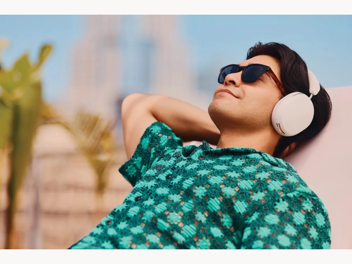 Person wearing white Sonos Ace headphones outdoors in warm weather
