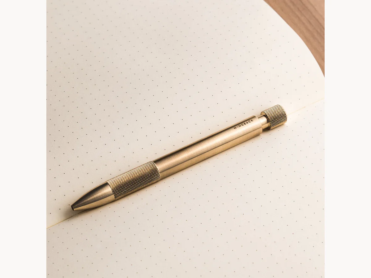 Wingback Mechanical Pen lying across a dotted notebook