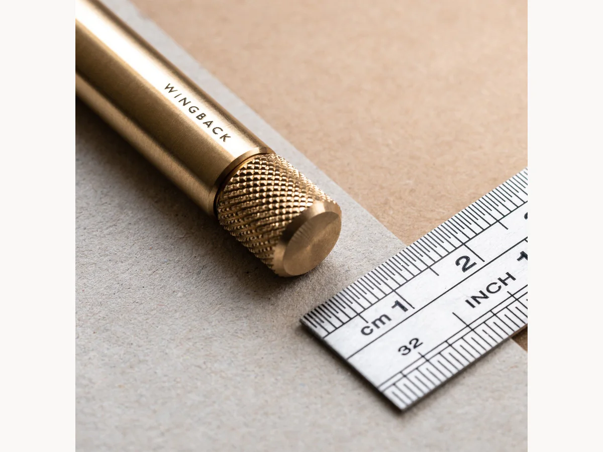 Close-up of Wingback Mechanical Pen knurled brass end beside a ruler